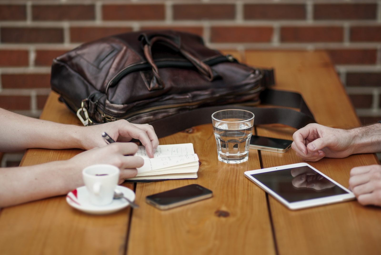 Two people at a table working through notes with a phone and a tablet.