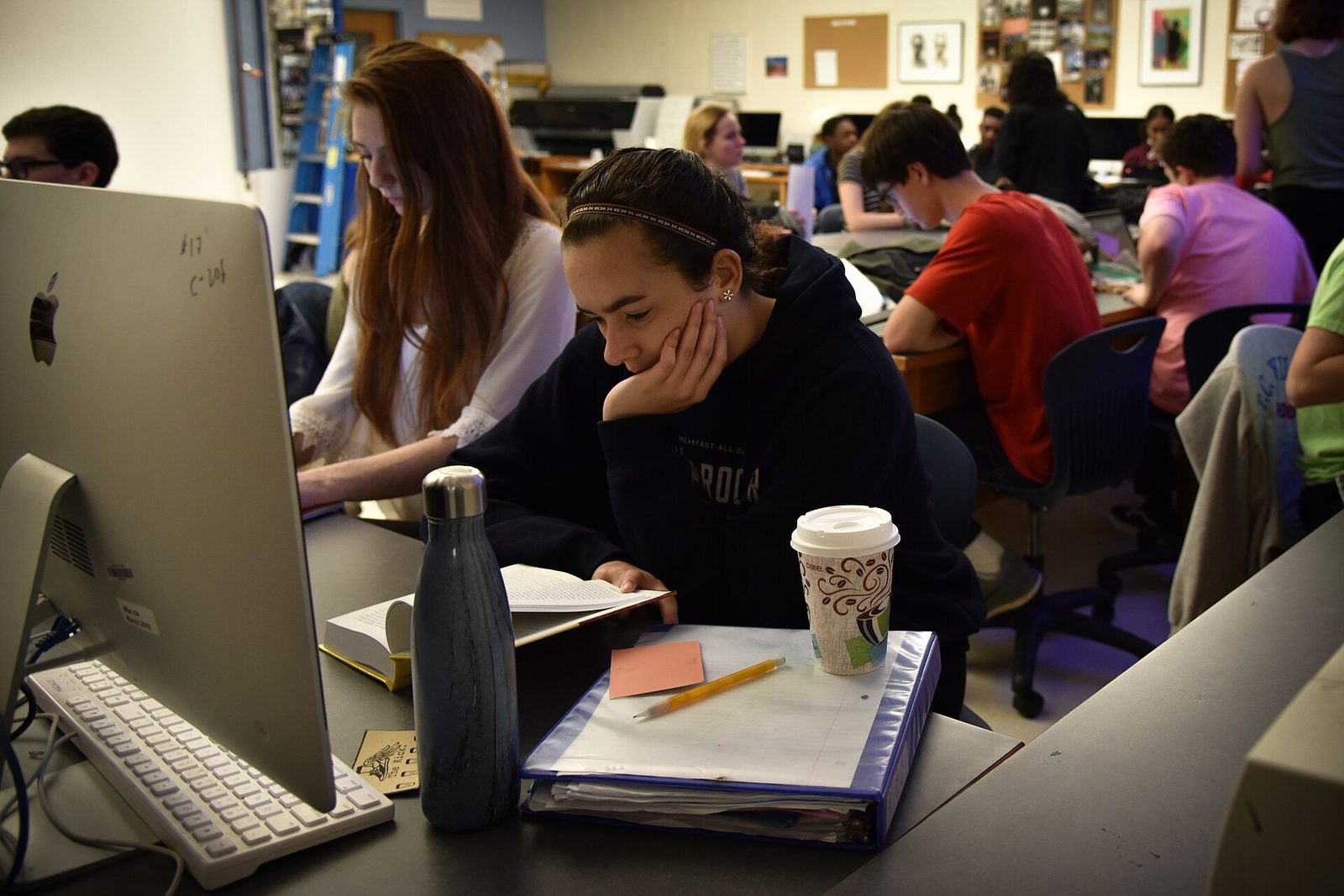 High school students working at rows of desktop computers in a school computer lab.