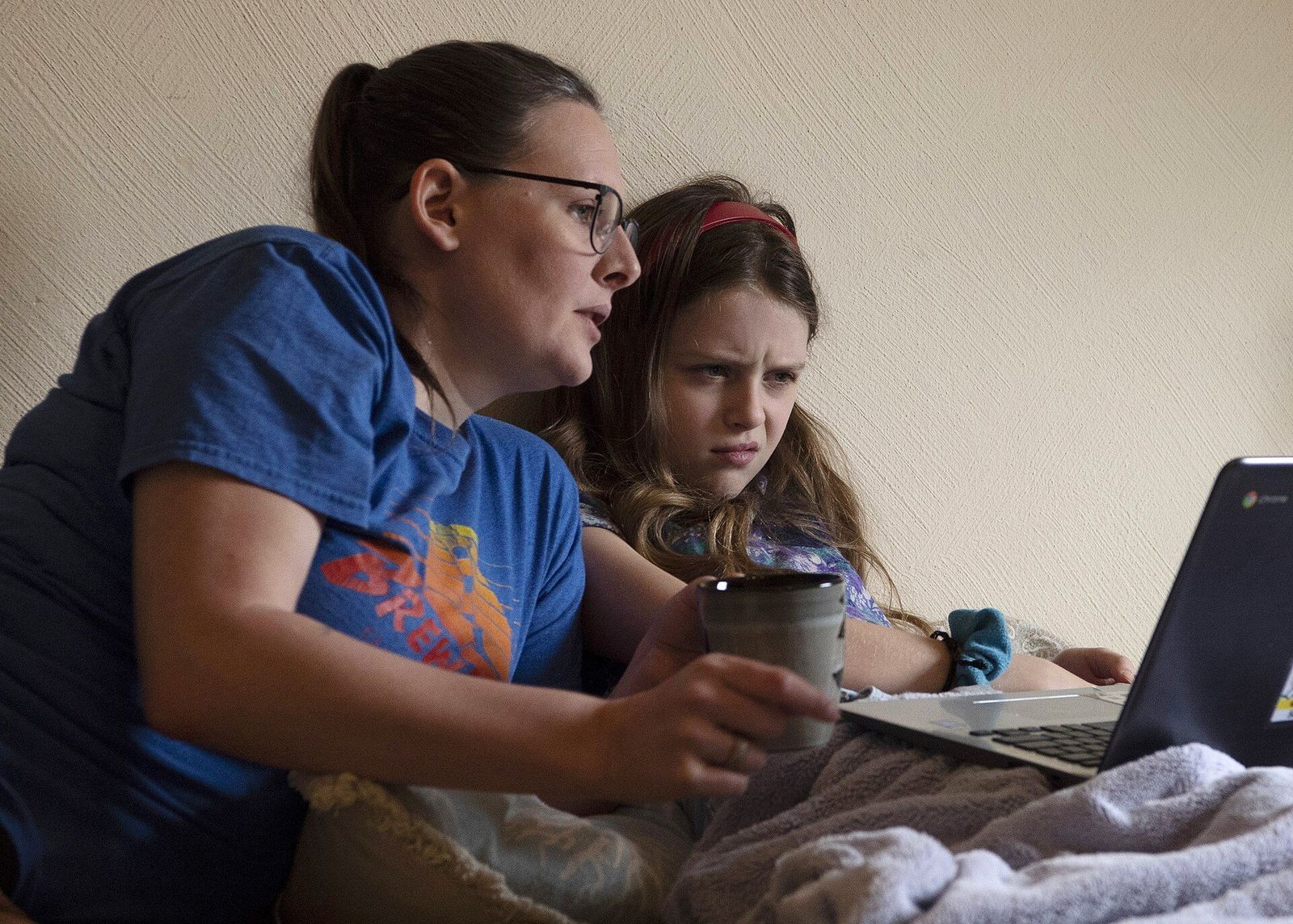 A mother and her daughter reading over a homework assignment together on a laptop at home.